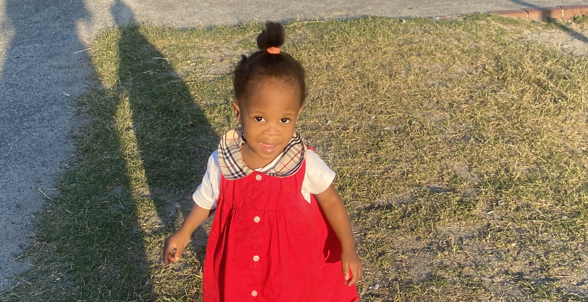 Young girl in a red dress smiling in the sunlight